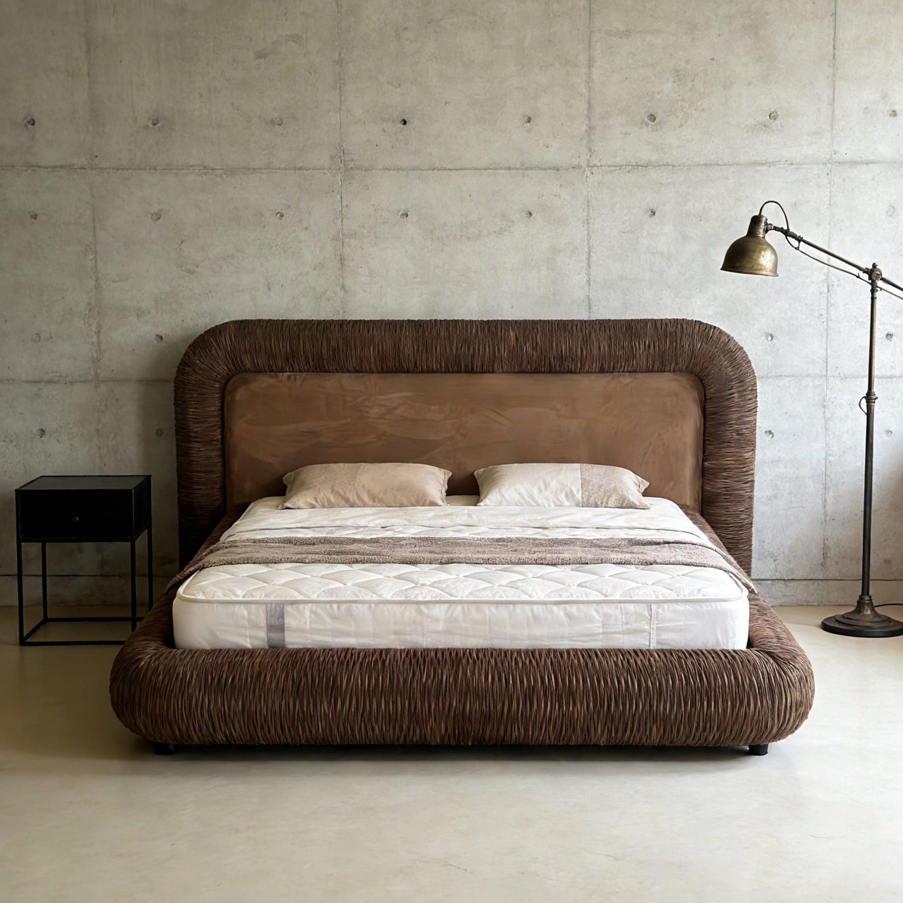 Modern bedroom with a brown upholstered bed against a concrete wall.