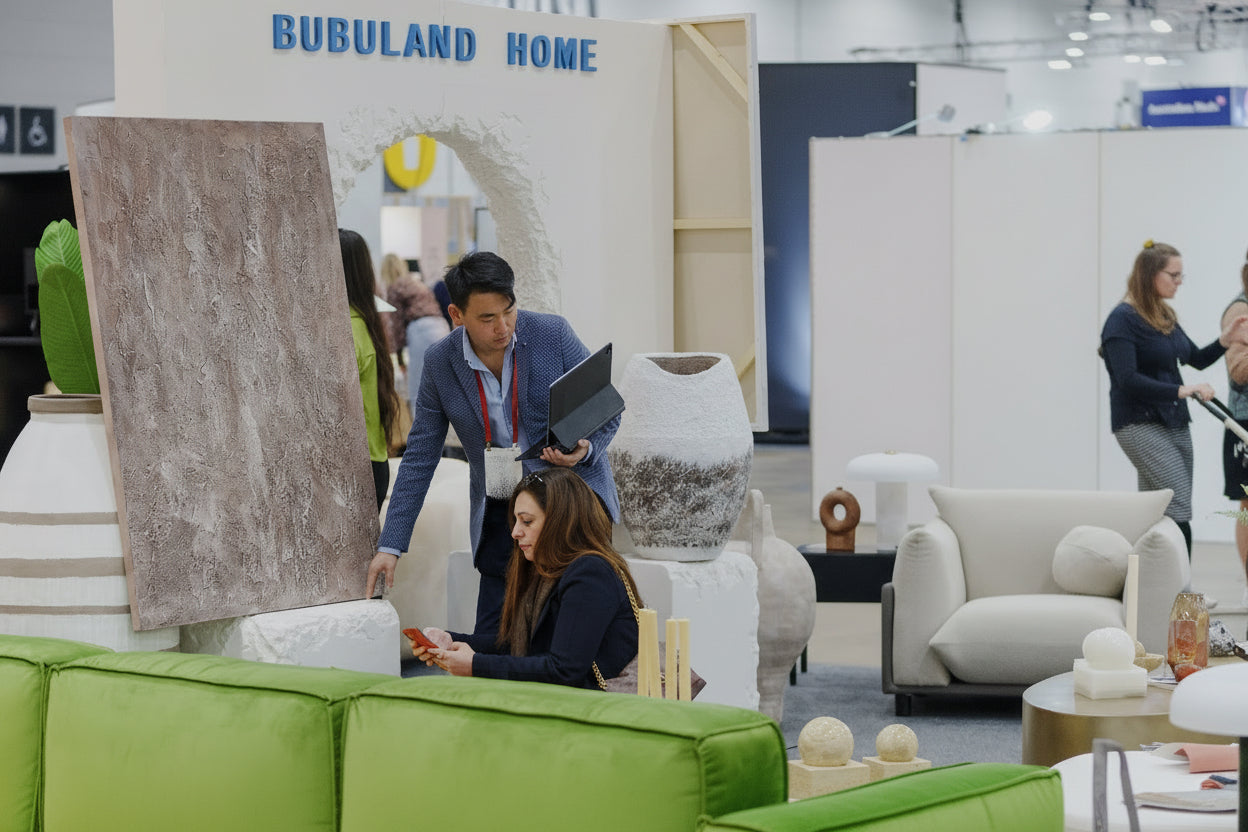 Furniture showroom with people interacting, featuring a green sofa and various decorative items.