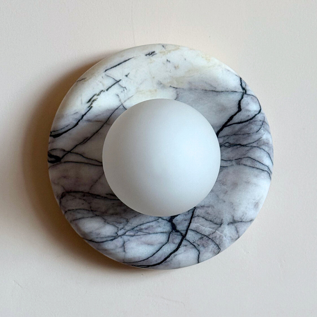 Marble-patterned circular object with a white sphere on a beige background