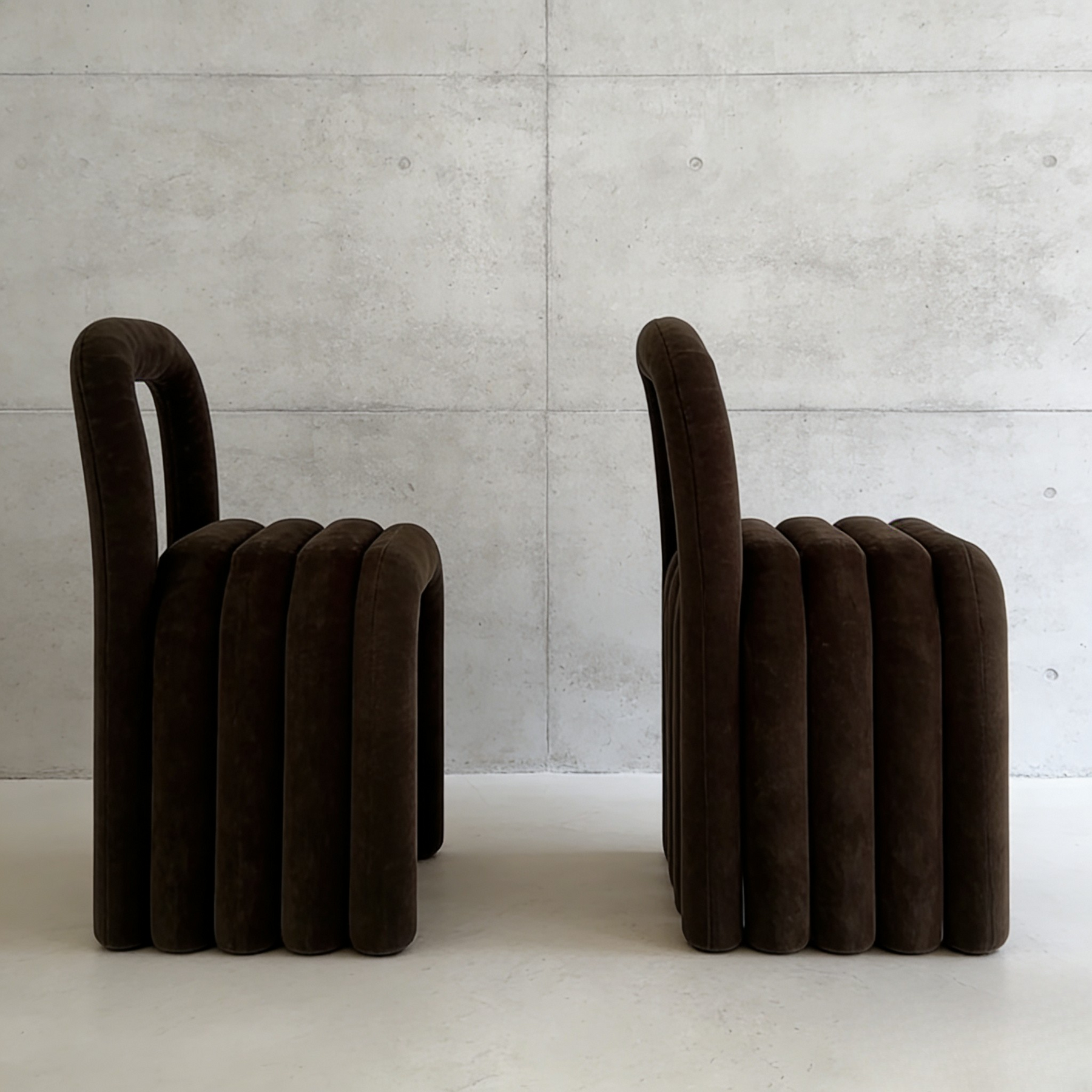 Two brown ribbed stools against a concrete wall.