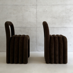 Two brown ribbed stools against a concrete wall.