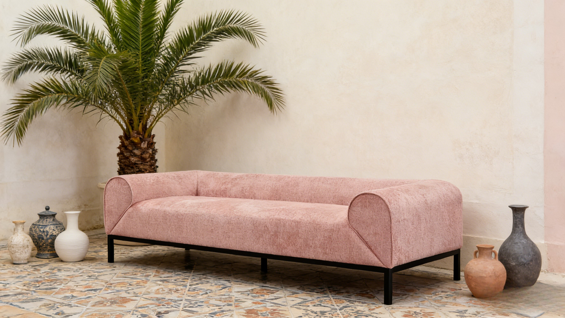 Pink sofa in a room with decorative vases and a palm tree