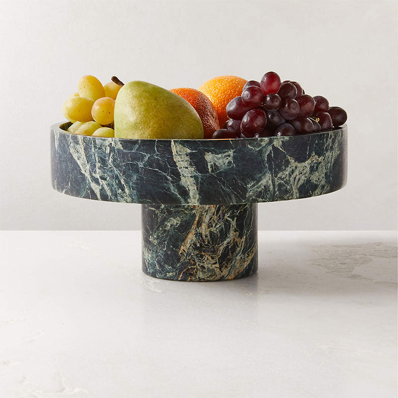 Marble fruit bowl with assorted fruits on a white surface